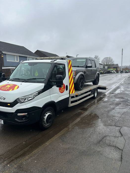 BnD Recovery truck transporting a grey Land Rover Discovery through a residential street