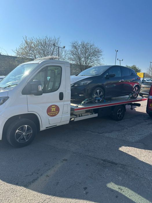 Dark Nissan hatchback secured on a BnD Recovery flatbed truck